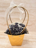 Flower Box Pure Vibe w złotej torebce z czarnymi kwiatami z wosku i białą kokardą – widok z przodu
