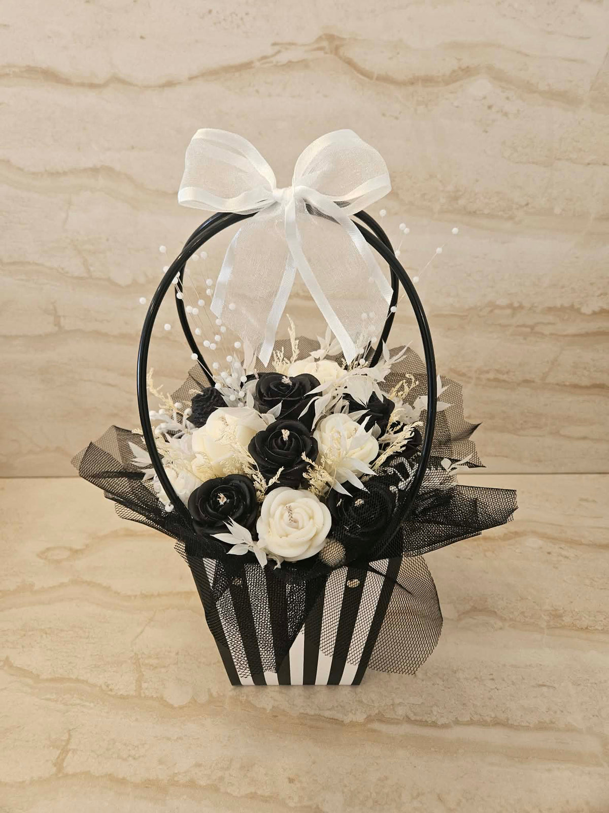 Flower Box z czarnymi i białymi kwiatami z wosku w czarno-białej torebce prezentowej – widok z przodu